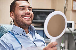 a patient checking his smile with a mirror