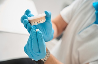 Dentist wearing blue gloves showing how model dental crown works