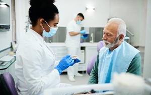 a dentist showing a patient a model of dentures 