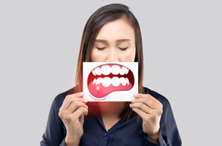 A woman holding an illustration of gum disease over her face