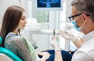 A dentist showing a dental implant to his patient