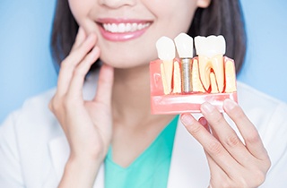 A woman holding an enlarged model of a dental implant