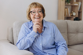 Woman in dental office looking at x-ray holding hand to face in pain