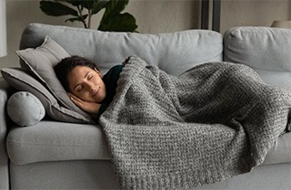 Woman sleeping peacefully on couch during tooth extraction recovery