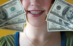 Woman with braces smiling and holding money