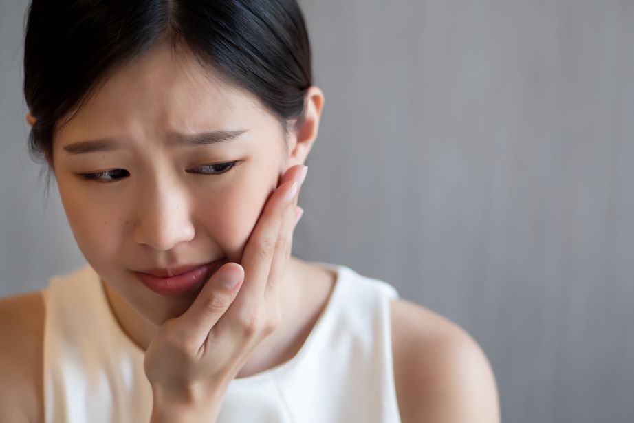 A woman holding her jaw in pain.